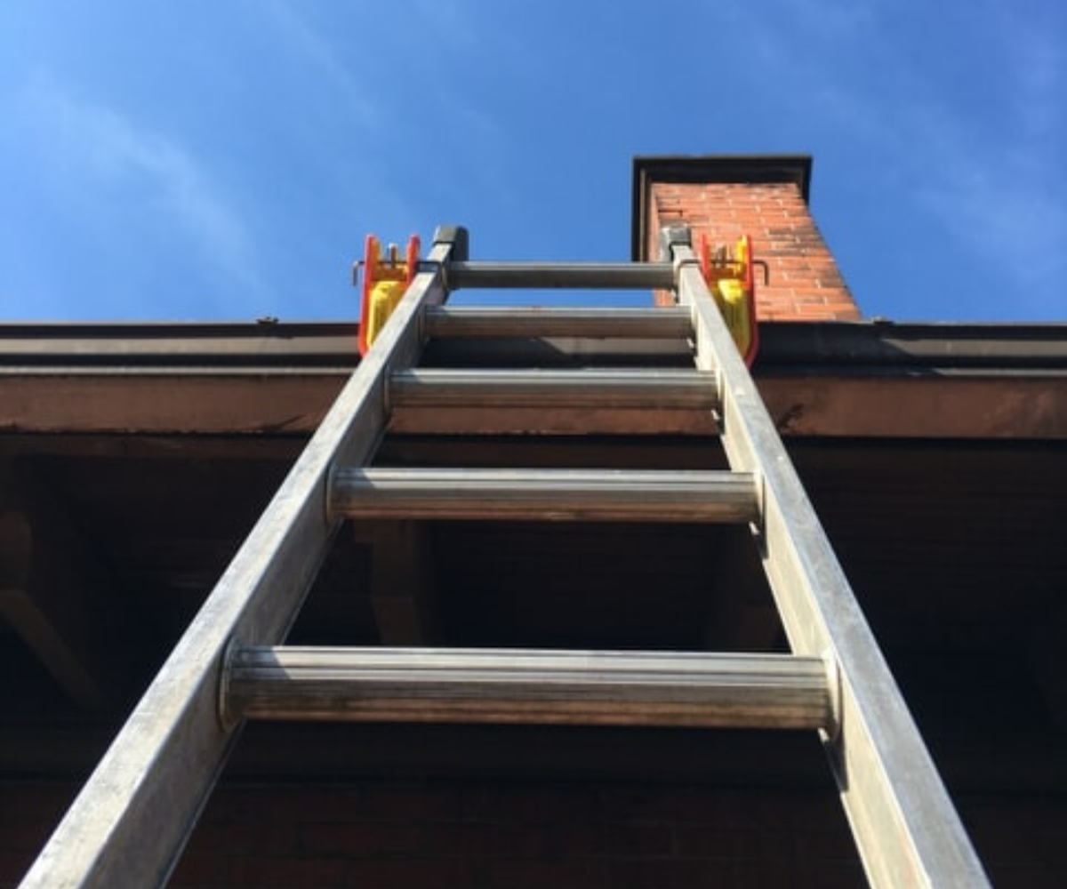 Lock Jaw Ladder Grip securing an extension ladder on a rooftop, ensuring safety and stability for climbing and maintenance.