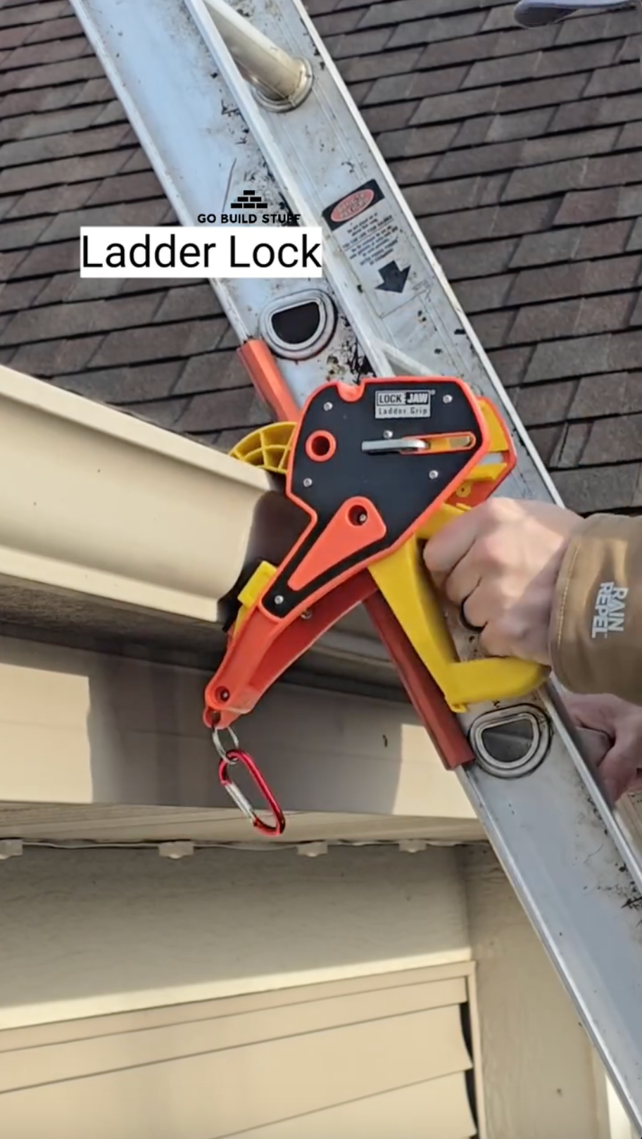 A hand secures a Lock Jaw Ladder Grip onto a ladder that's positioned against a gutter. Text overlay says "Ladder Lock".
