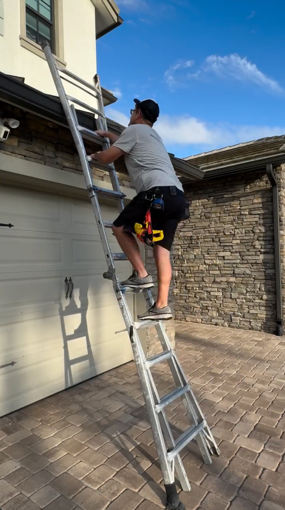 A man climbing a ladder attached to a house.
