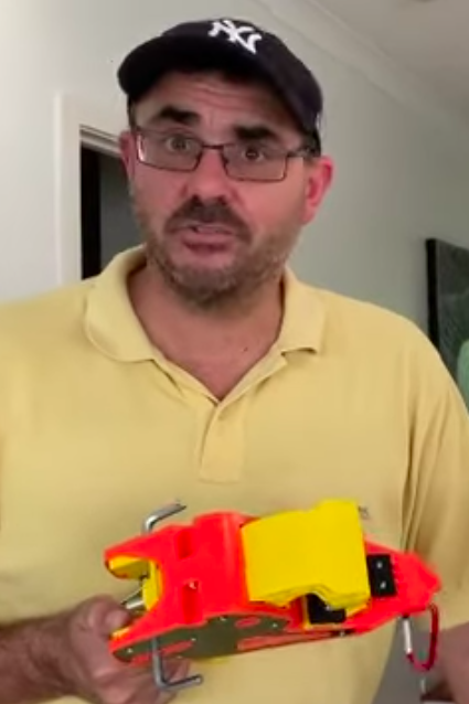 A man with glasses and a cap holds a Lock Jaw Ladder Grip in front of him.