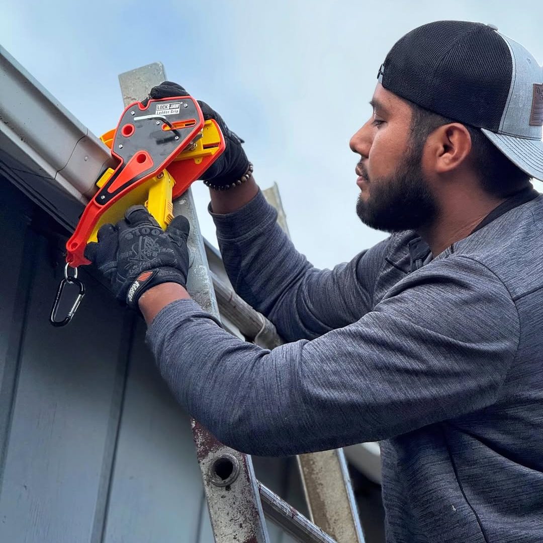 Solar installer clamping a Lock Jaw Ladder Grip onto the gutter by hand