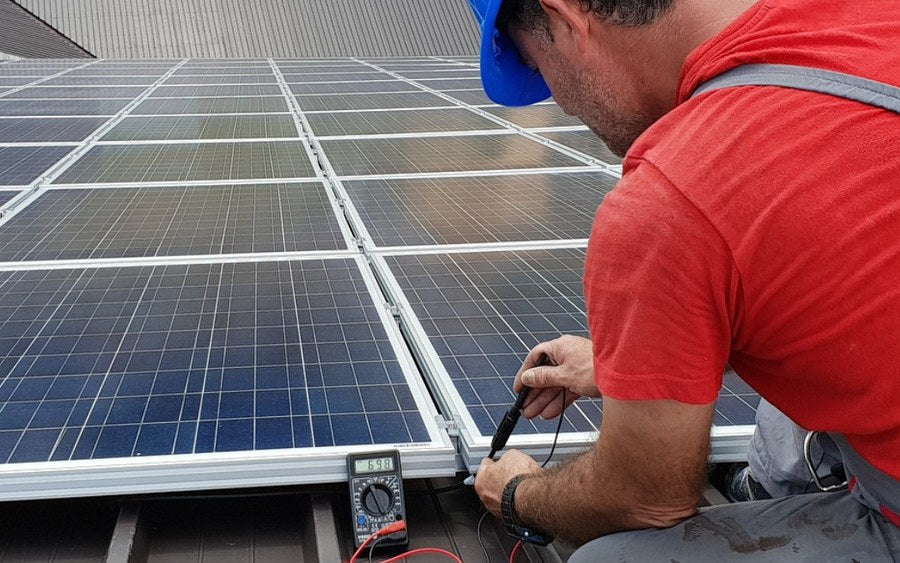 Electrician working on rooftop AC and solar circuits
