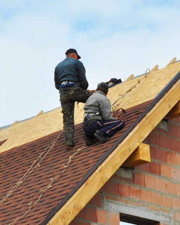 Two workers on a pitched roof inspecting the structure