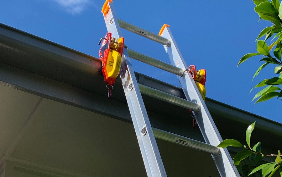 Extension ladder secured to a residential gutter with two Lock Jaw Ladder Grips