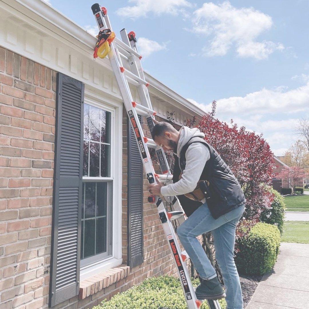 An extension ladder set up and secured at the gutter of a house
