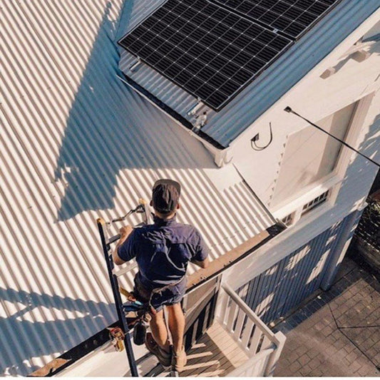 Climbing onto a metal roof with the ladder secured at the gutter
