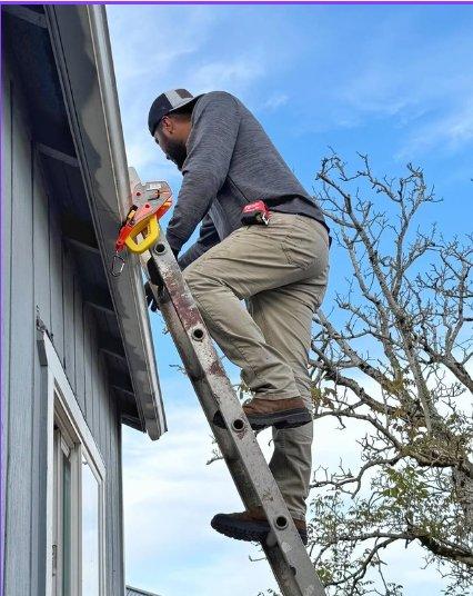 Climbing to a ladder secured at the gutter, with a tool pouch on the belt