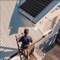 Working solo on a metal roof, with the ladder secured at the gutter