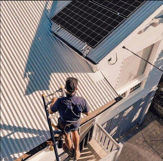 Working solo on a metal roof, with the ladder secured at the gutter