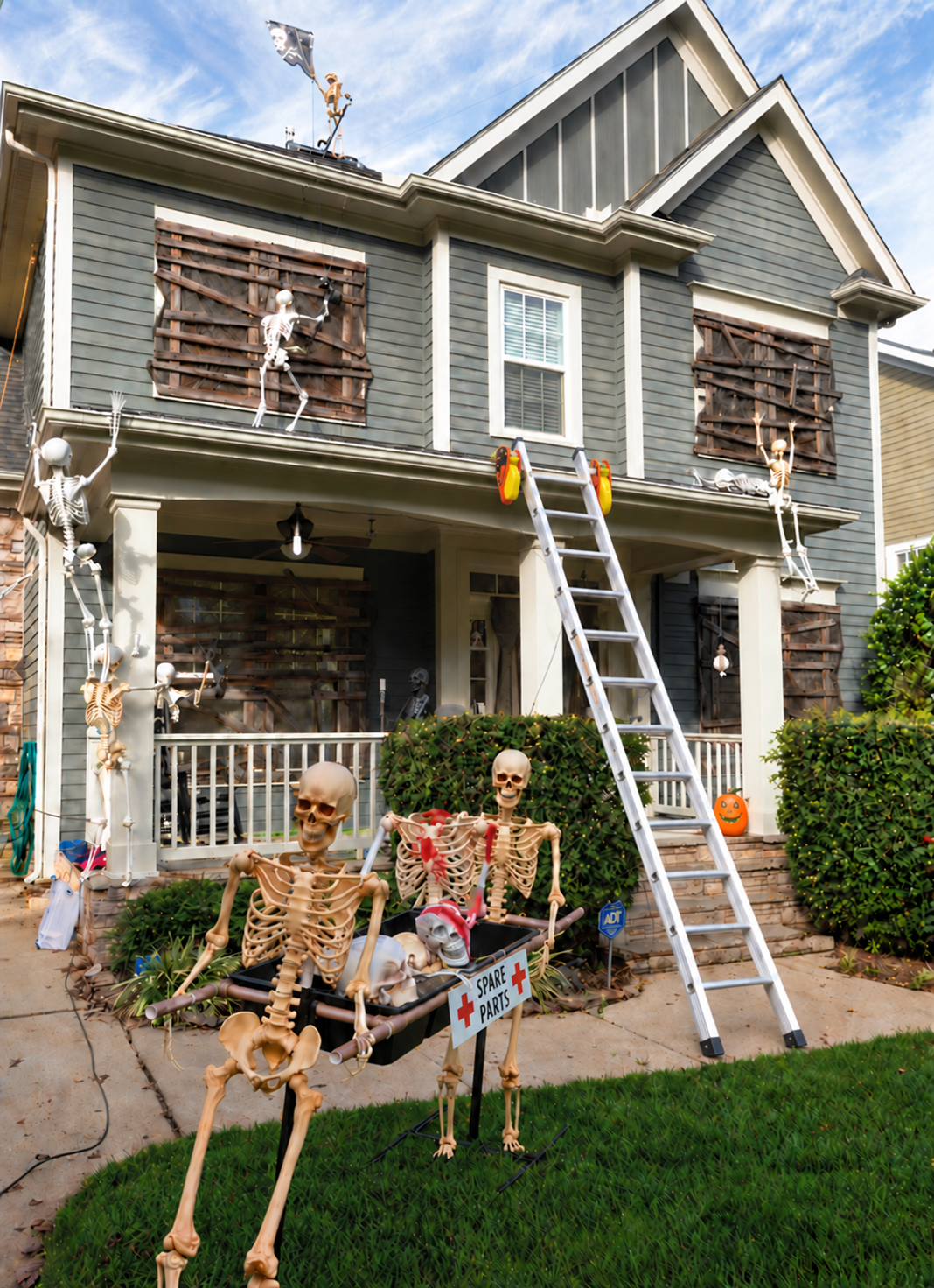 Halloween-decorated house with skeleton props and a ladder showing Lock Jaw grips at the gutter