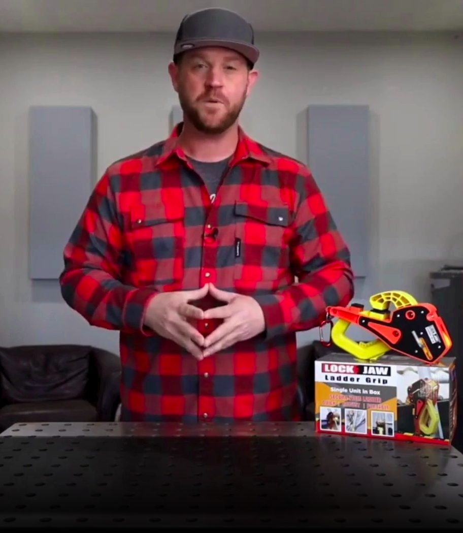 A man with a beard and a baseball cap holds a Lock Jaw Ladder Grip and its packaging.