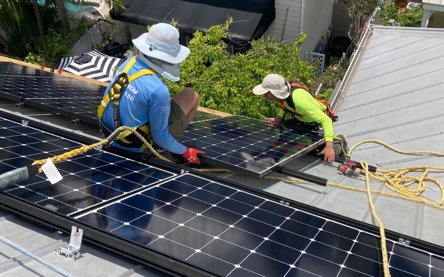 Solar installers fitting rooftop panels on a residential home