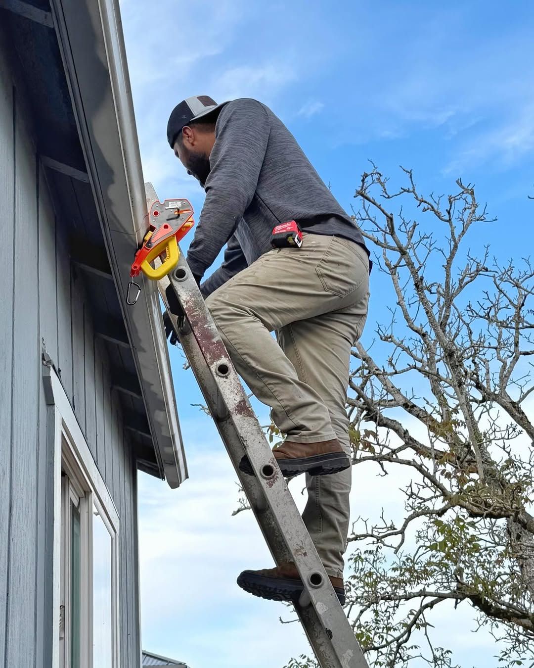 Solar installer climbing an extension ladder locked to the gutter with a Lock Jaw Ladder Grip