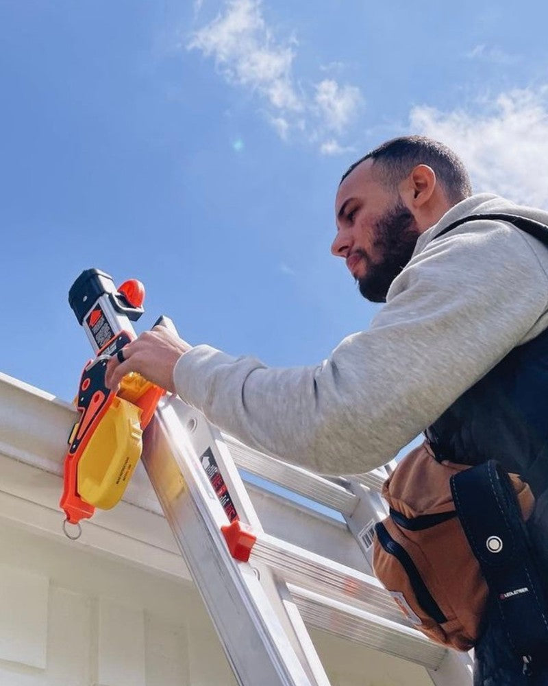 A tradie fitting a Lock Jaw Ladder Grip to an extension ladder at a gutter